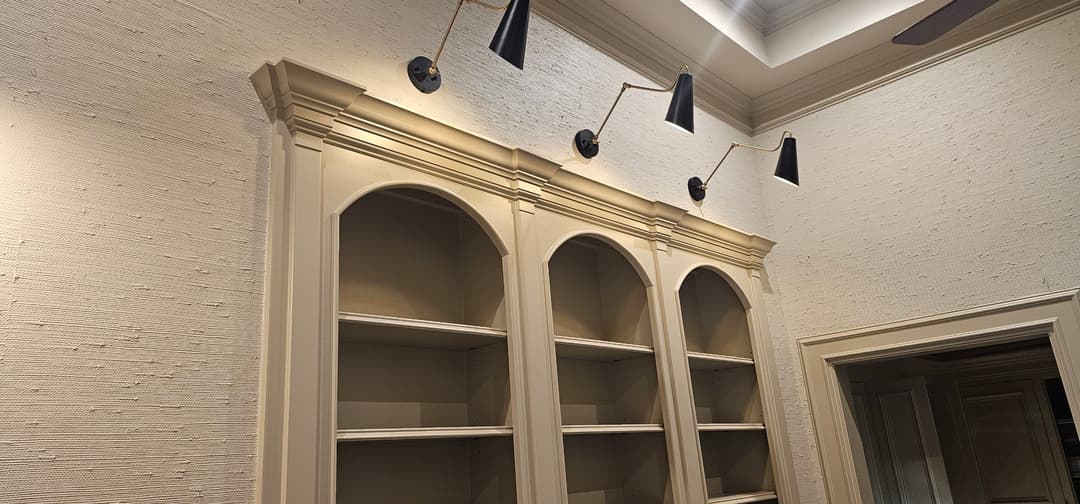 Elegant wall shelves with three modern sconces in a stylish interior setting.