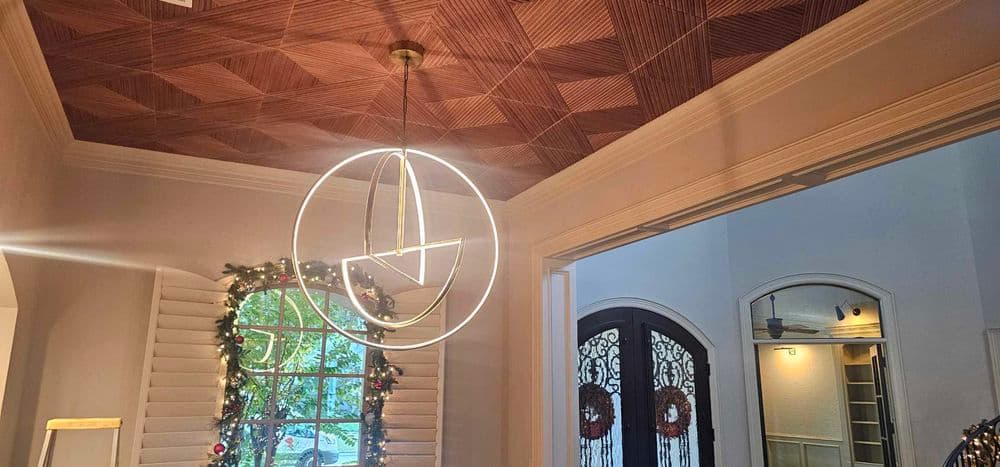 Modern interior with geometric wood ceiling and circular pendant light, festive decor visible.